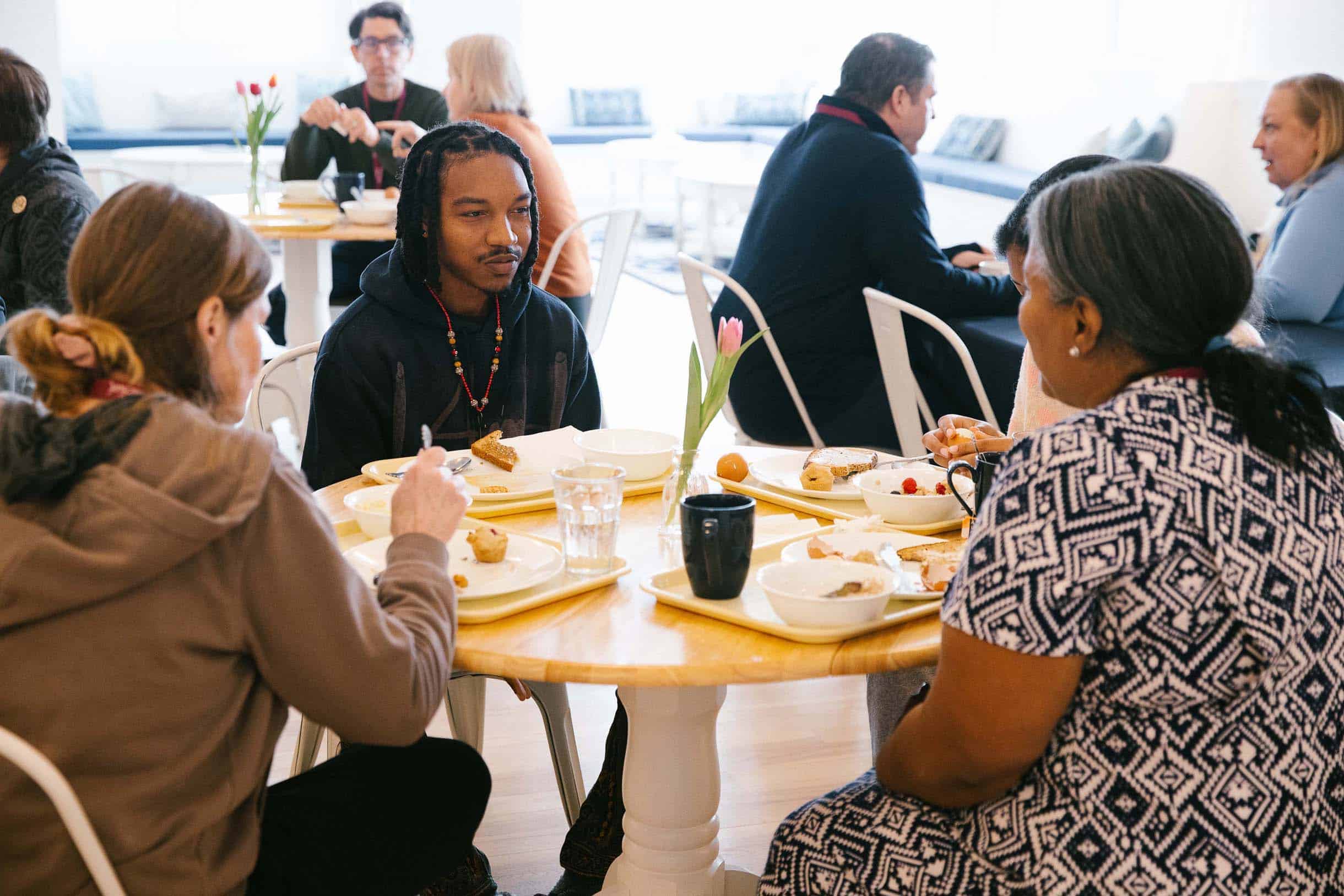 Retreat participants engage in thoughtful conversation while eating breakfast in the sunlit dining room.