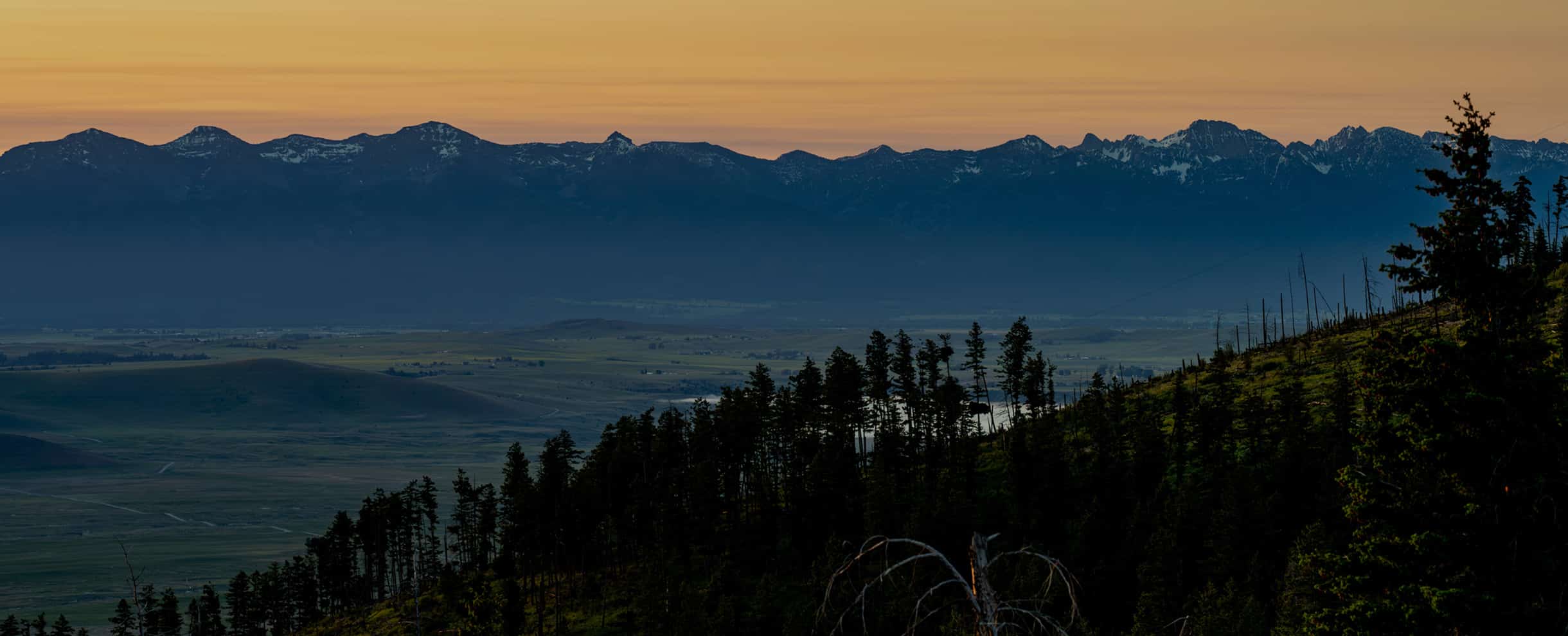 Panoramic sunset view of the Mission Mountains over a valley from the Namchak Retreat Ranch.