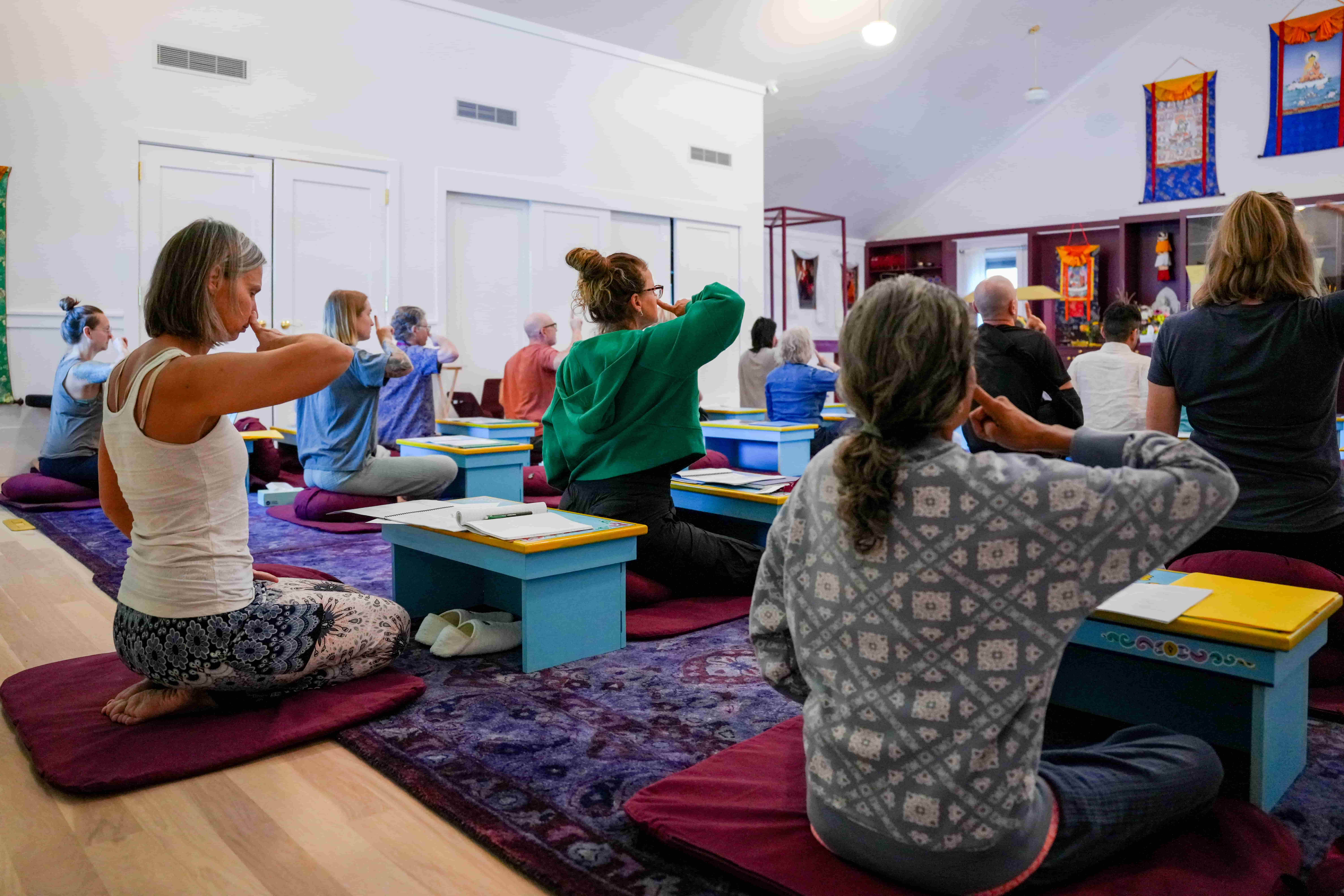 Participants practicing guided meditation during a Green Tara Retreat group session in a peaceful indoor setting