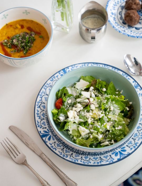 Fresh forest-to-table meal featuring a green salad, warm soup, roasted vegetables, and wholesome dishes served on a clean white table
